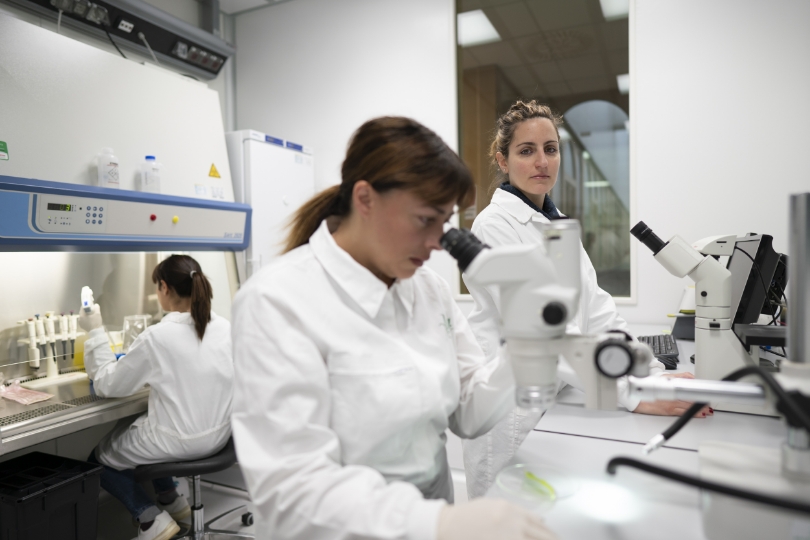 Tre ricercatrici sono in laboratori mentre osservano risultati al microscopio