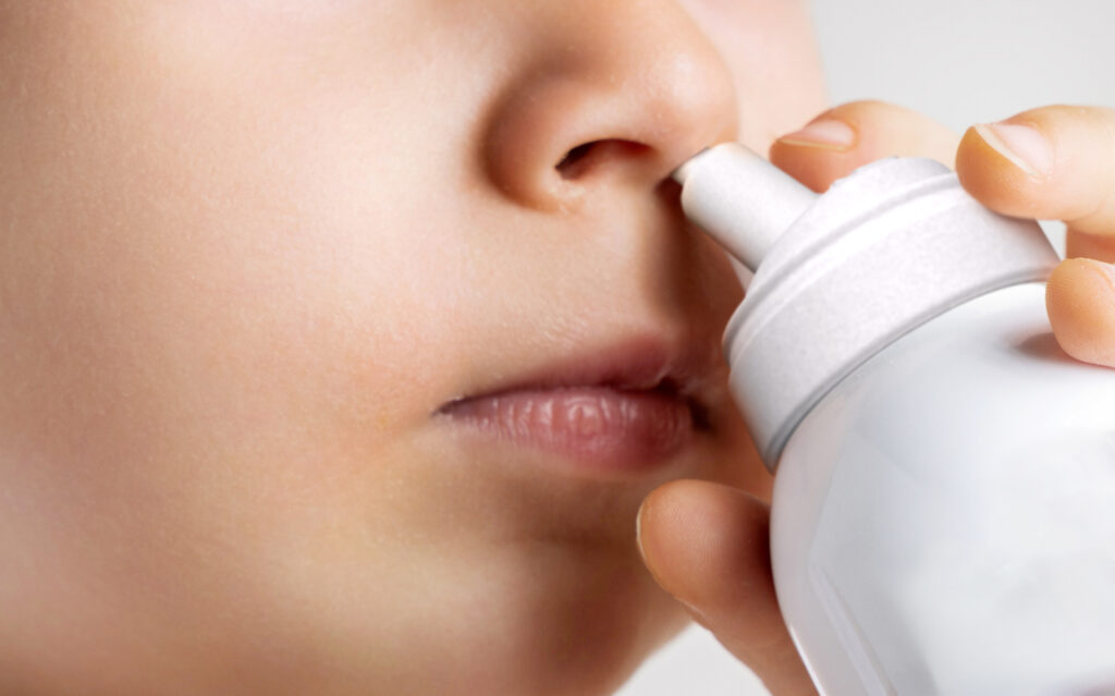 Un bambino sta facendo un lavaggio nasale con uno spray