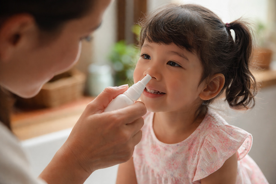 Una mamma sta facendo un lavaggio nasale alla figlia sorridente